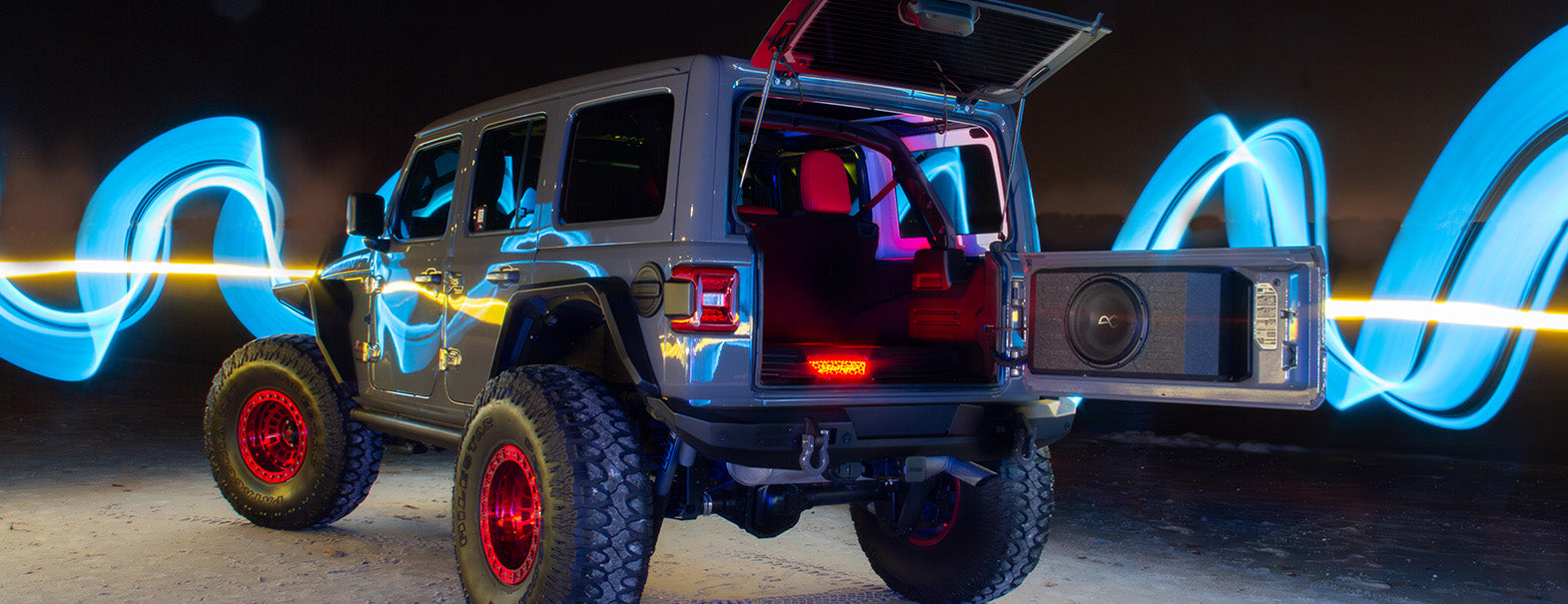 Jeep with open trunk and laser lights on a dark background